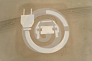 Closeup on an white eletric car charging logo , painted on a ground of a renewable energy parking spot