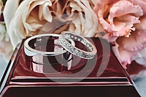 Closeup of white golden wedding rings on floral background