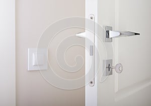 Closeup of white interior doors. Lock with key and chrome door handle