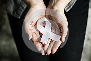 Closeup of white ribbon on hands palm bone cancer anti violence awareness