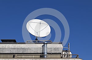 Closeup of a White satellite dish antenna on the roof against blue sky