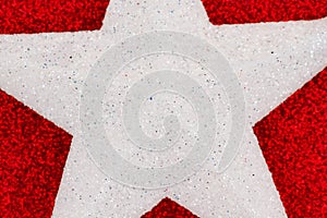 Closeup of a white star on red glitter textured paper