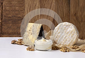 Closeup of whole camember,cheese for whisky,sweet soft cheese in the glass jar,walnut on the white table against rustic wooden bac