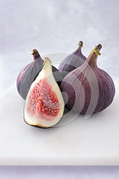 Closeup of Whole and Quarter Figs on White Marble Board