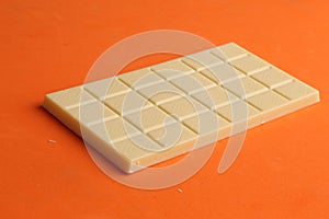 Closeup of a whole white chocolate bar isolated on an orange background