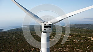 Closeup of a wind turbine against green mountains