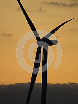 Closeup of a wind turbine captured against a cloudy sky at sunset