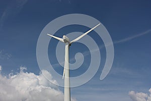 Closeup of a wind turbine in the cloudy sky background