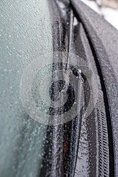 Closeup of wipers and frosted car windshield covered with ice