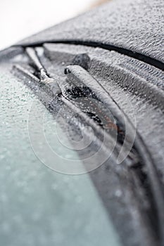 Closeup of wipers and frosted car windshield covered with ice