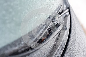 Closeup of wipers and frosted car windshield covered with ice