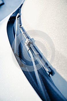 Closeup of wipers and frosted car windshield covered with ice