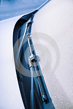 Closeup of wipers and frosted car windshield covered with ice