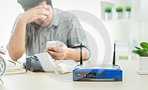 closeup of a wireless router and a man using smart phone on living room at home ofiice, network lost