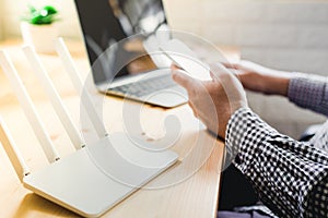 closeup of a wireless router and a man using smartphone on living room at home ofiice photo