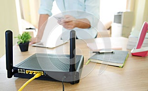 closeup of a wireless router and a man using smartphone on living room at home ofiice