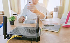 Closeup of a wireless router and a man using smartphone on living room at home ofiice