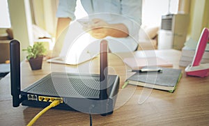 Closeup of a wireless router and a man using smartphone on living room at home ofiice