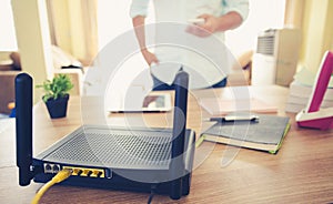 Closeup of a wireless router and a man using smartphone on living room at home ofiice photo