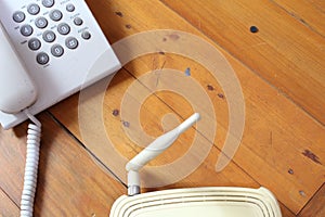 Closeup of a wireless router and telephone on wooden table