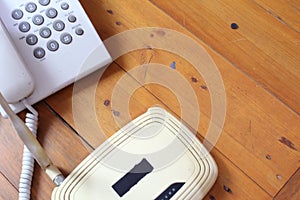 Closeup of a wireless router and telephone on wooden table