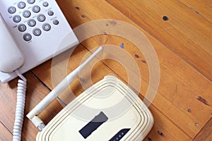 Closeup of a wireless router and telephone on wooden table