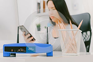 Closeup of a wireless router and a woman using smartphone on living room at home ofiice