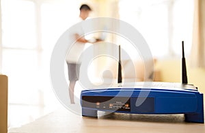 Closeup of a wireless router and a young man using Laptop and notebook computers on living room at home with a window in the