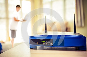 Closeup of a wireless router and a young man using Laptop and notebook computers on living room at home with a window in the