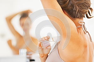 Closeup on woman applying roller deodorant on underarm