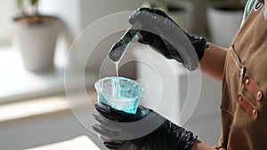 Closeup of woman artist kneads mixing art epoxy resin in plastic cup working in art studio workshop