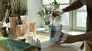 Closeup of woman artist kneads mixing art epoxy resin in plastic cup working in art studio workshop