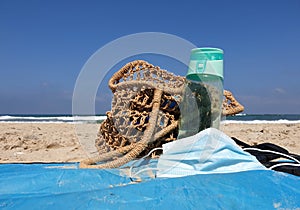 Closeup on woman beach bag, water bottle and face mask on a beach sand