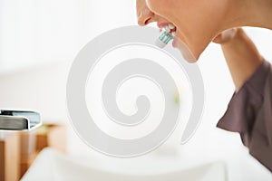 Closeup on woman brushing teeth in bathroom