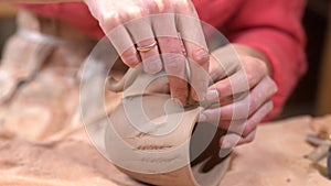 Closeup of woman ceramist clinging the handle to the raw clay cup.