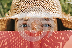 Closeup of woman covering her face with a red book