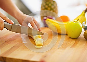 Closeup on woman cutting banana on cutting board