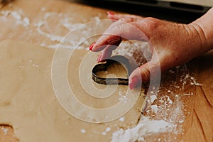 Closeup of a woman cutting the dough with a heart-shaped cookie cutter