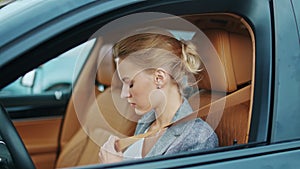 Closeup woman driver buckling seat belt at car. Woman sitting at front seat