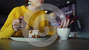 Closeup of woman eating dessert. Young fmale enjoying the time and and eating a cake in cafe.