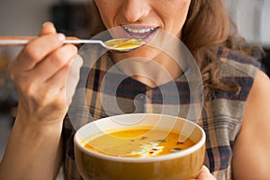 Closeup on woman eating pumpkin soup in kitchen