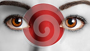 Closeup woman eyes japanese flag painted face.