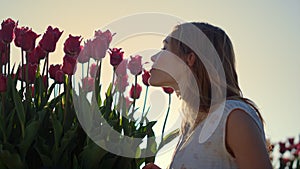 Closeup woman face profile smelling flowers in sun reflecction bright sunny day.