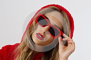 Closeup woman face in red sunglasses isolated on white background. Girl in red hoodie sweatshirt and red lips makeup. Fashion