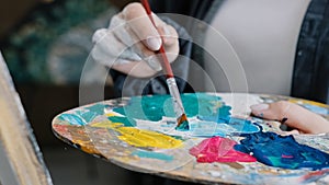 Closeup woman female hand artist painter paints draws creating new art work on canvas in workshop lesson of painting