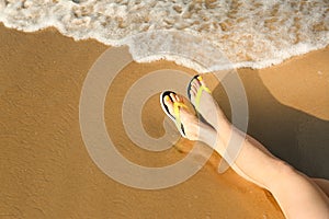 Closeup of woman with flip flops on sand, space for text. Beach accessories
