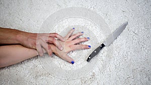 Closeup of woman grabbing a knife while being attacked by man