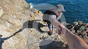 Closeup of woman hand helping male friend climb the mountain top.