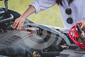 Closeup of woman hand holding battery cable copper wire for repairing broken car by connect battery with red and black line to