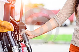 Closeup of woman hand holding a fuel pump at a station.